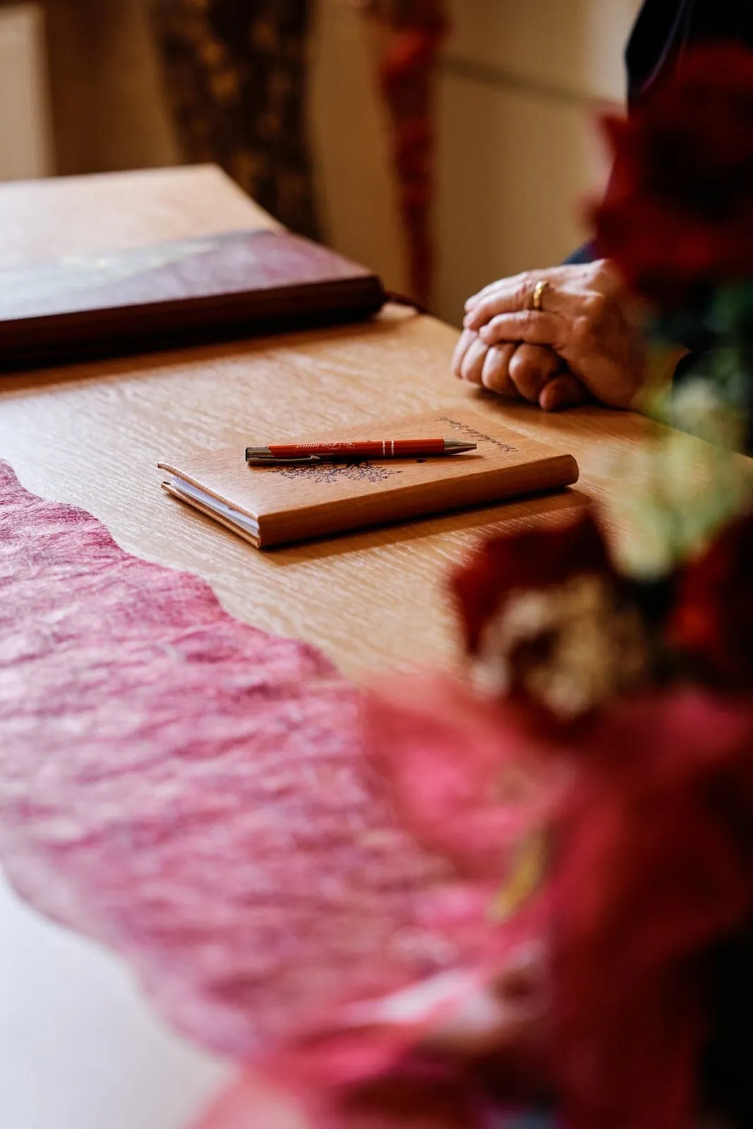 Die Hände des Trauredner liegen locker auf dem Tisch, vor ihm liegt das Stammbuch und der Kugelschreiber bereit für das Hochzeitspaar.