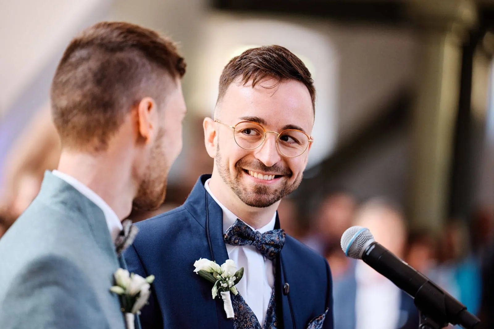 Strahlender Bräutigam lächelt liebevoll seinen zukünftigen Ehemann an. Eine bewegende Szene der Freude bei einer gleichgeschlechtlichen Hochzeit.