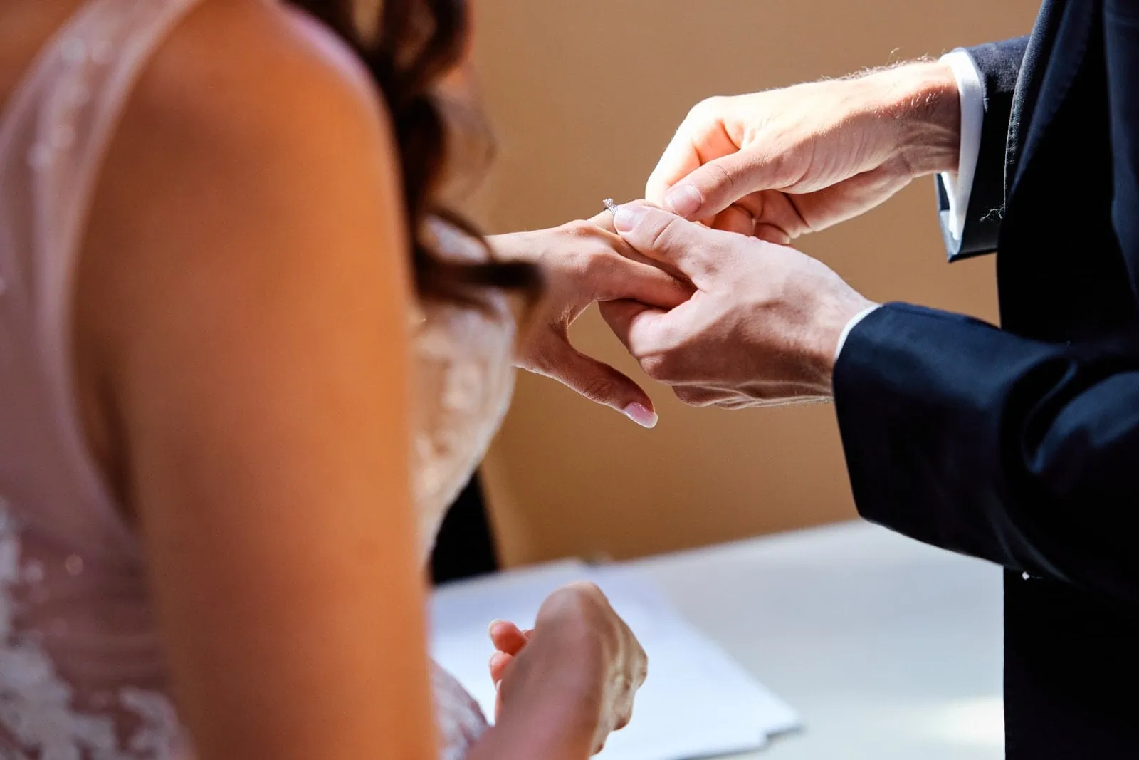 Eine sehr besondere Nahaufnahme der Hände, der Bräutigam setzt der Braut zärtlich den Ehering auf.