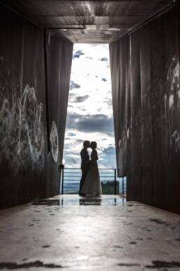 Die fein fotografierte Linienführung setzt das Brautpaar sofort in den Fokus. Man sieht sie nur als Silhouette und eine Wolkenpracht erstreckt sich im Hintergrund.